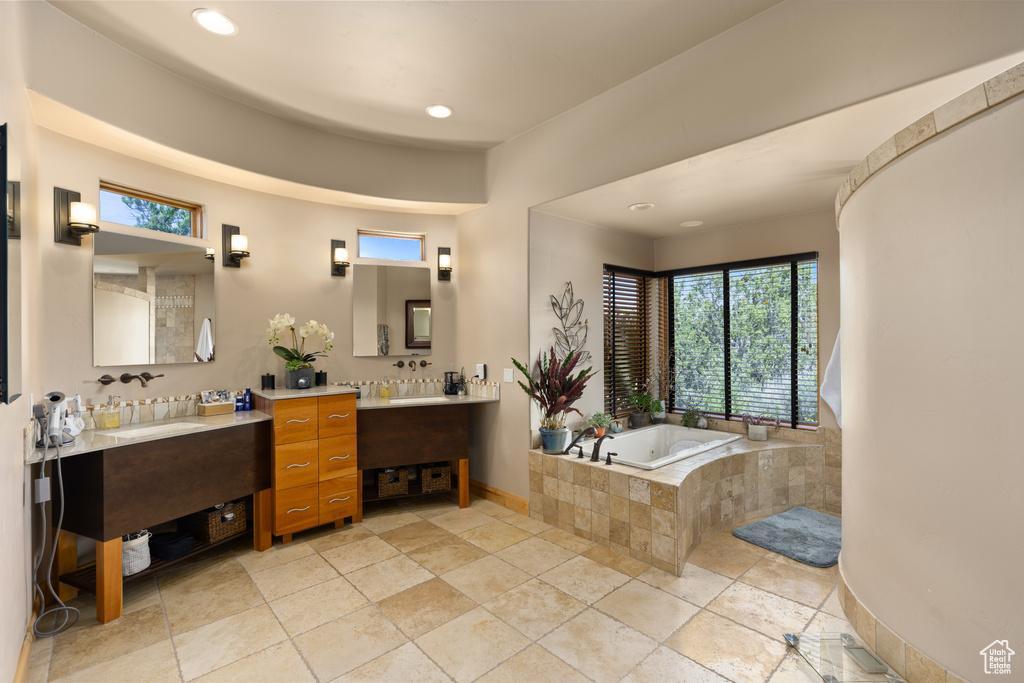 Bathroom featuring tile flooring, tiled bath, and double sink vanity