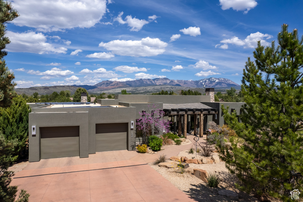 Adobe home featuring a garage, a mountain view, and a pergola