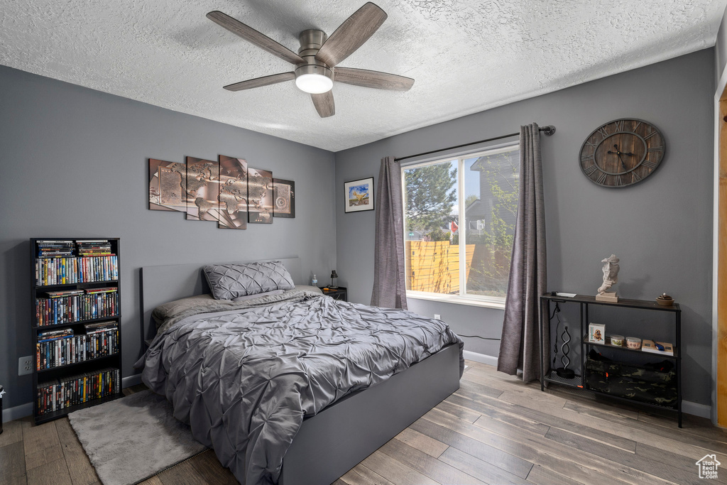 Bedroom featuring hardwood / wood-style floors, ceiling fan, and a textured ceiling