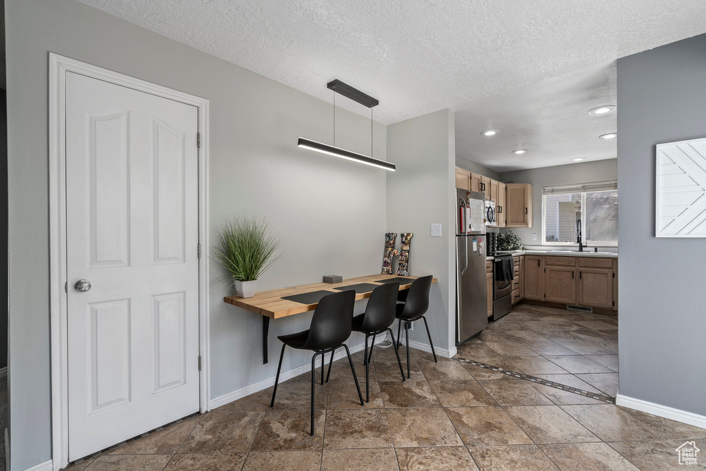 Kitchen featuring electric range, pendant lighting, tile floors, and stainless steel fridge