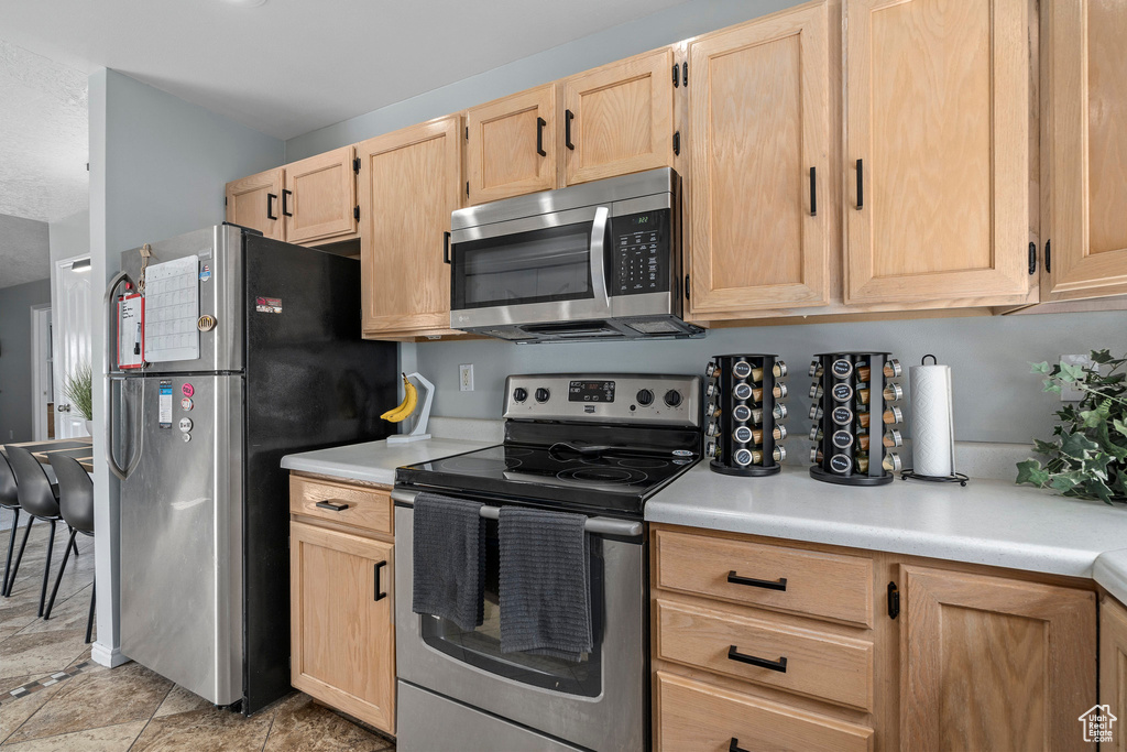 Kitchen featuring light brown cabinets, light tile floors, and stainless steel appliances