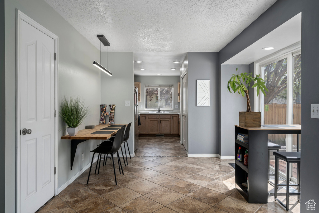 Interior space featuring a healthy amount of sunlight, pendant lighting, tile floors, and stainless steel fridge
