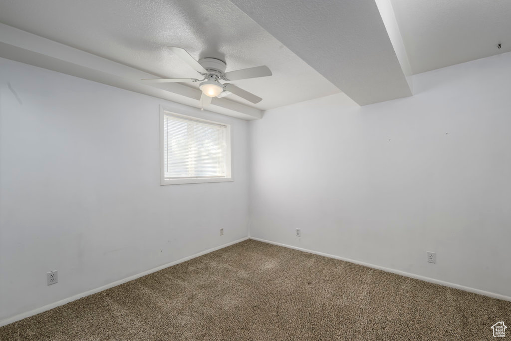 Spare room with a textured ceiling, ceiling fan, and carpet