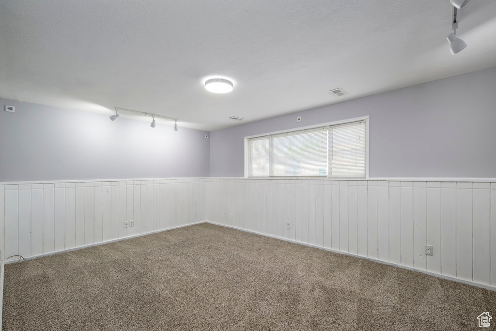 Unfurnished room with rail lighting and carpet flooring