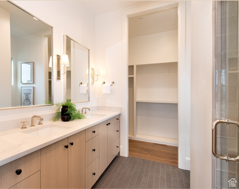 Bathroom featuring dual sinks, oversized vanity, a shower with shower door, and tile flooring