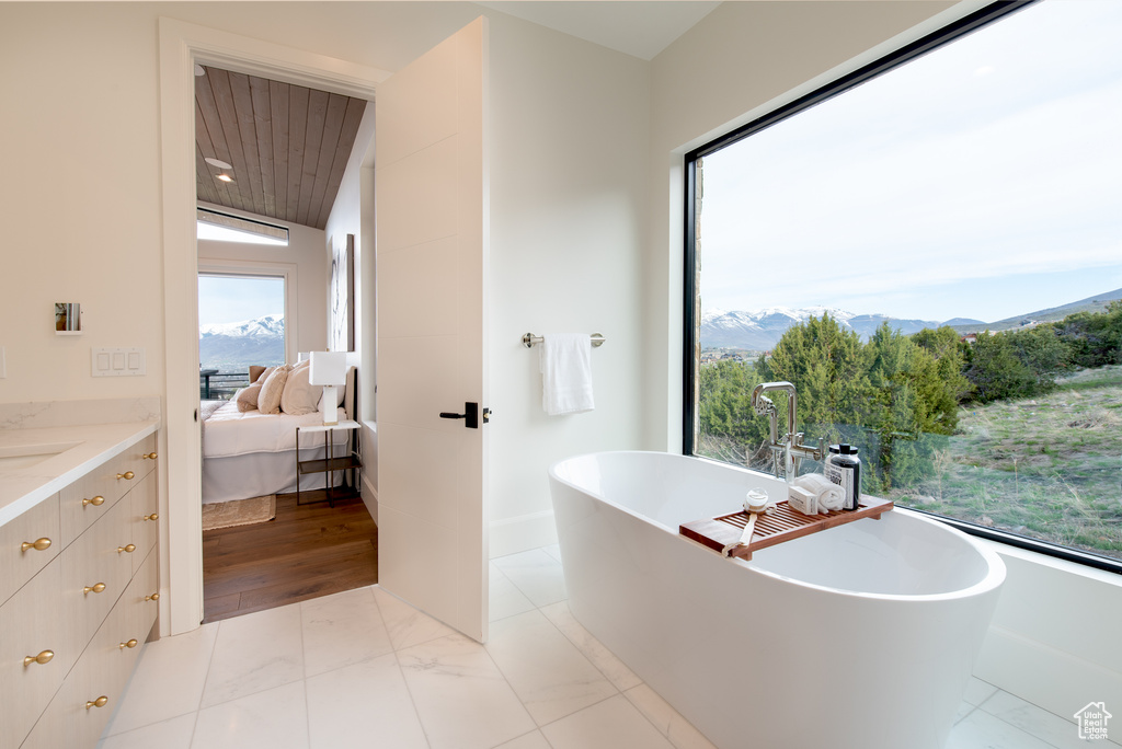 Bathroom featuring a mountain view, wood-type flooring, a bath, and lofted ceiling
