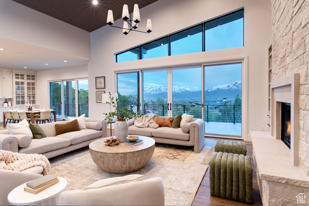 Living room featuring a mountain view, a stone fireplace, wood-type flooring, and a towering ceiling