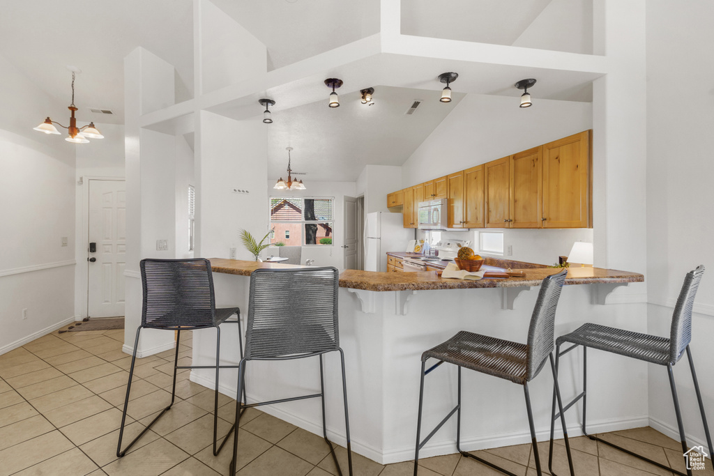 Kitchen with high vaulted ceiling, white appliances, kitchen peninsula, and light tile floors