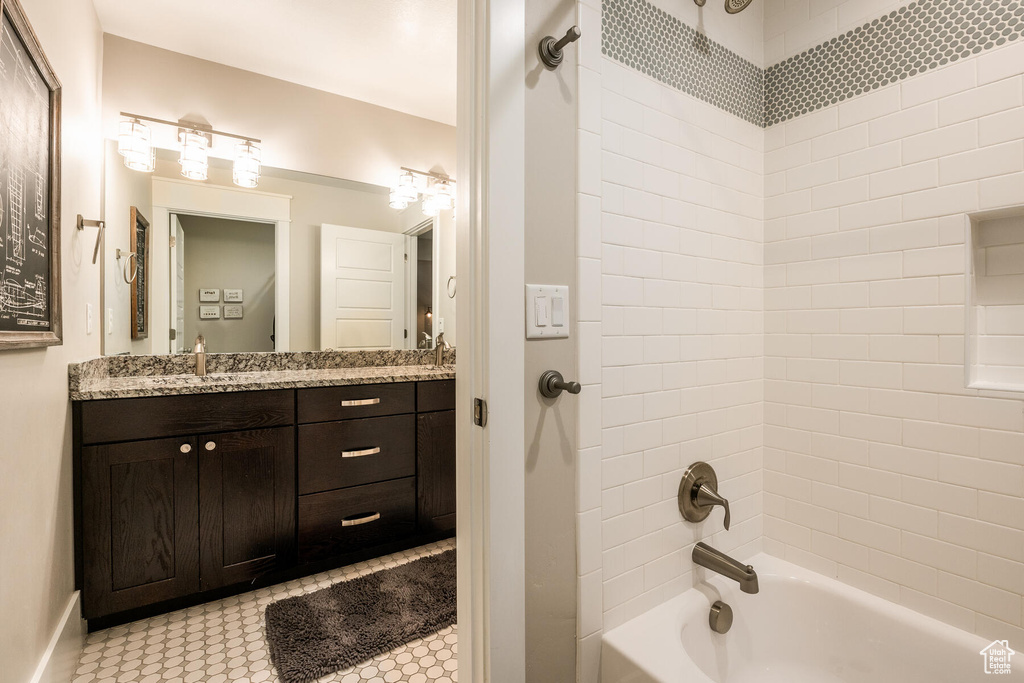 Bathroom with tiled shower / bath, vanity, and tile floors