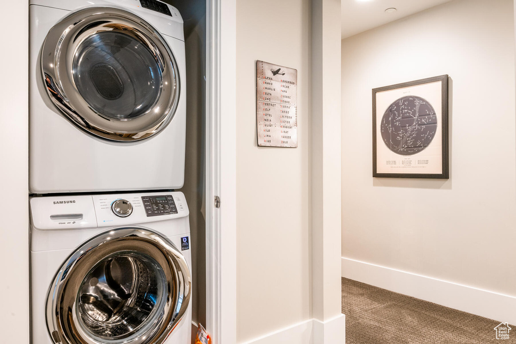 Washroom featuring stacked washer and clothes dryer and carpet floors