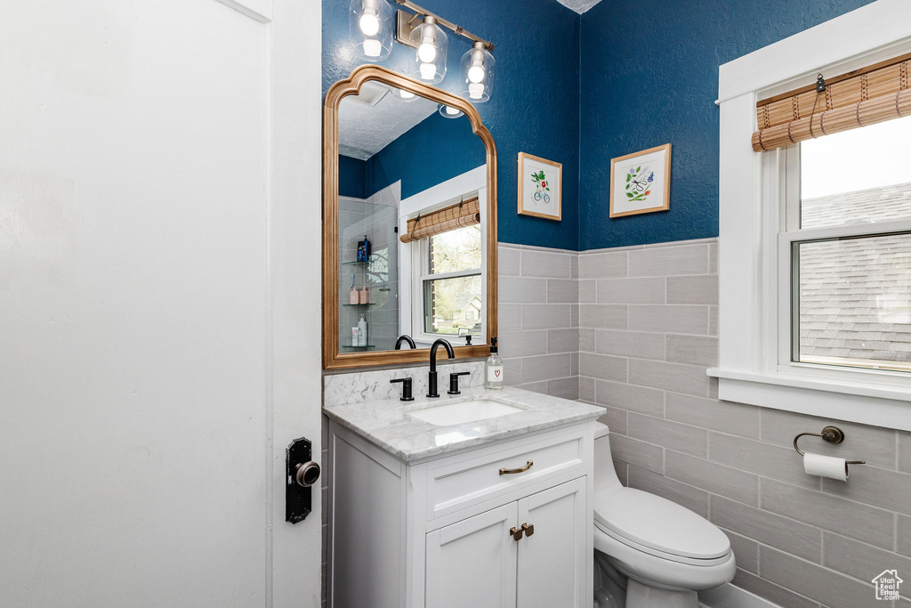 Bathroom featuring oversized vanity, tile walls, and toilet