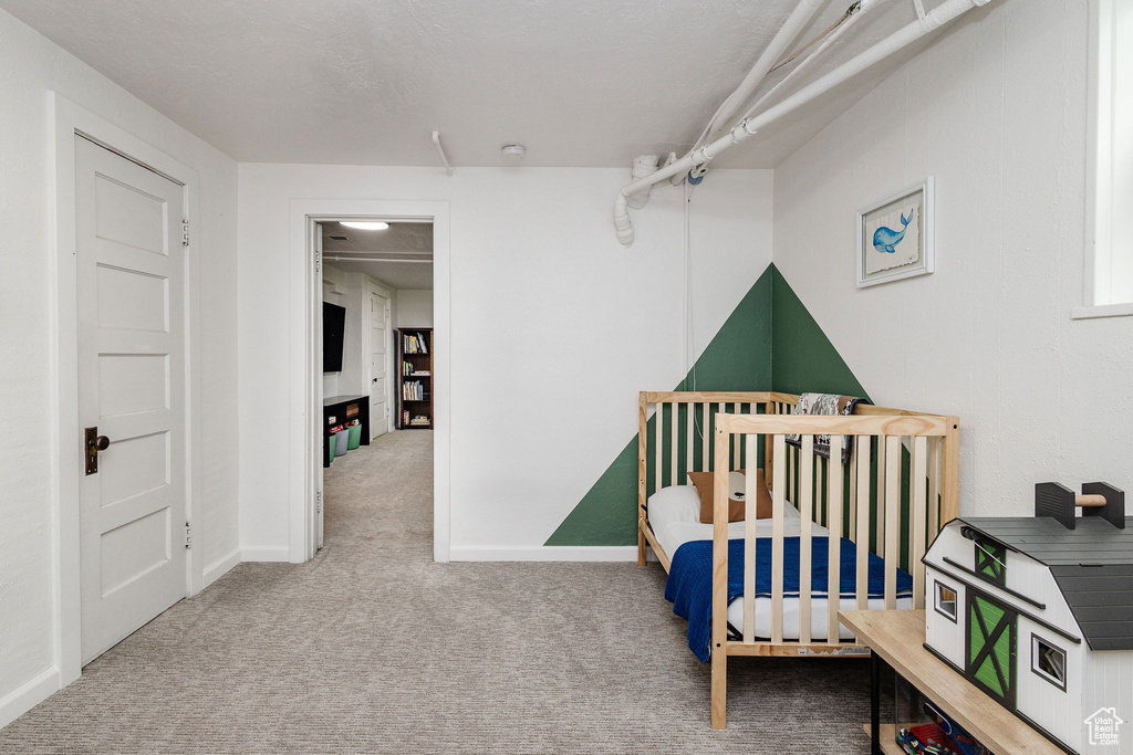 Carpeted bedroom featuring a nursery area