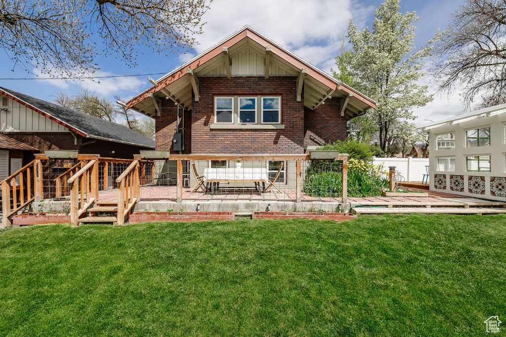 Back of property featuring a yard, a wooden deck, and a patio