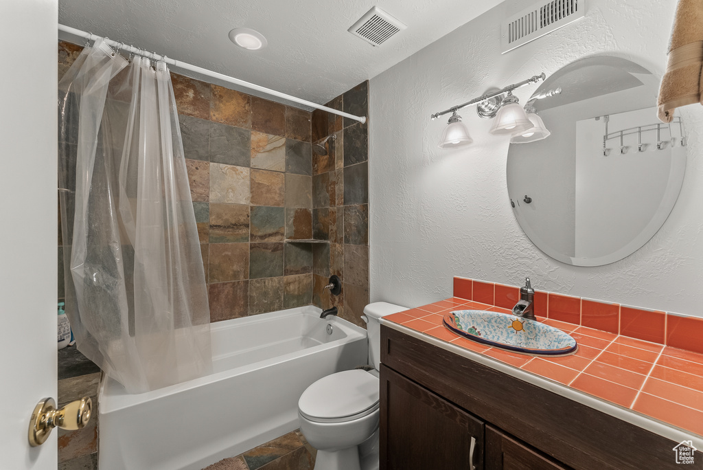 Full bathroom with large vanity, shower / bath combination with curtain, tile floors, and toilet