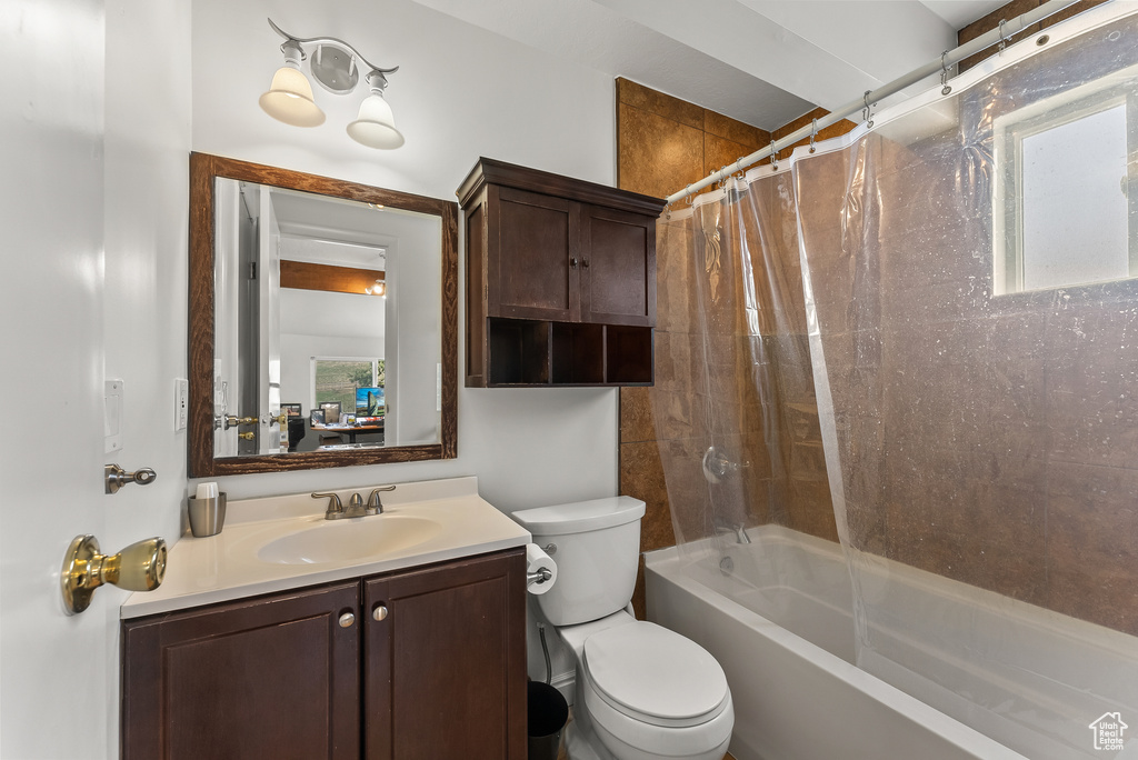 Full bathroom featuring plenty of natural light, oversized vanity, toilet, and shower / bathtub combination with curtain