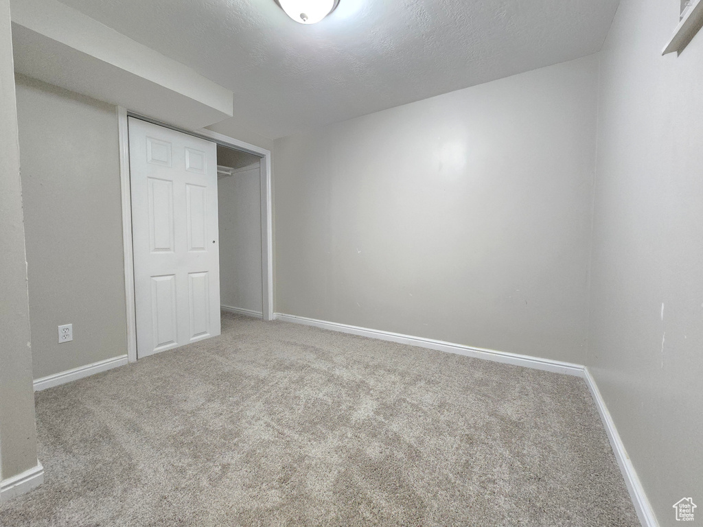 Unfurnished bedroom featuring carpet, a closet, and a textured ceiling