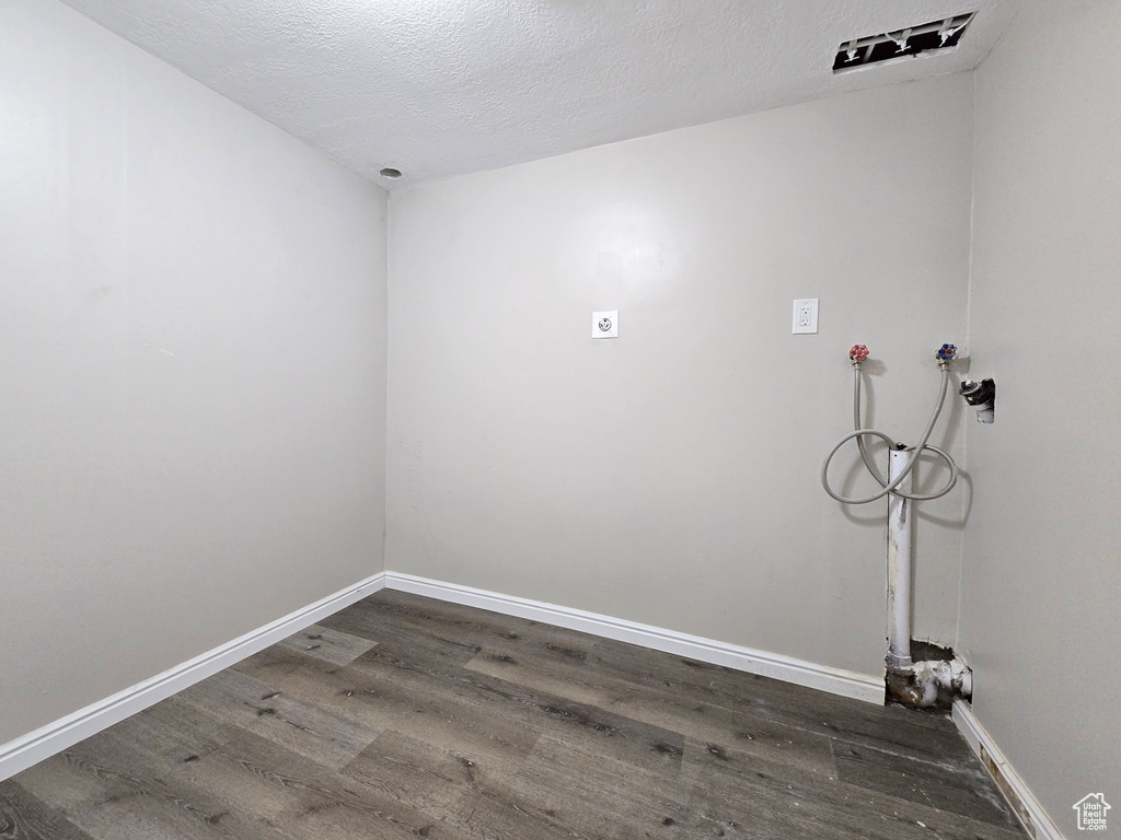 Clothes washing area with hookup for a washing machine, a textured ceiling, and hardwood / wood-style floors