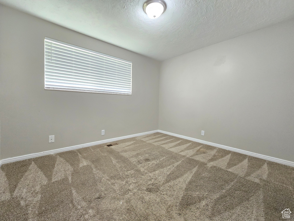 Empty room with a textured ceiling and carpet