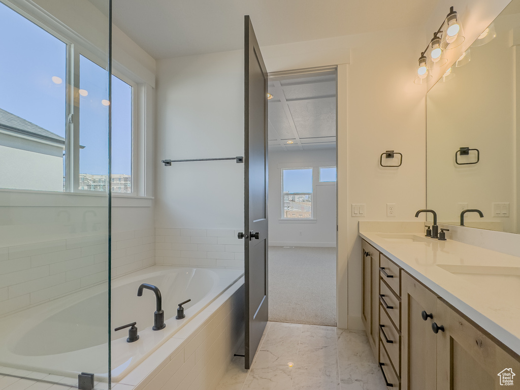 Bathroom featuring vanity, tile floors, and tiled bath