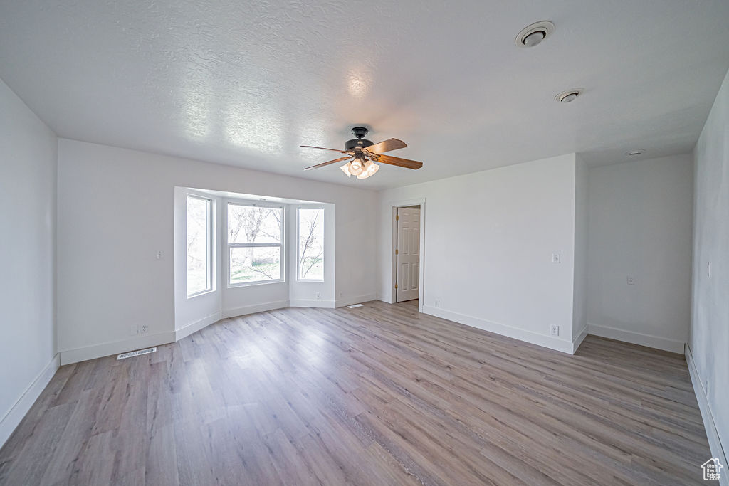 Unfurnished room with wood-type flooring, ceiling fan, and a textured ceiling