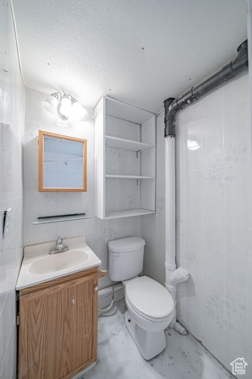 Bathroom featuring concrete flooring, toilet, vanity, and a textured ceiling