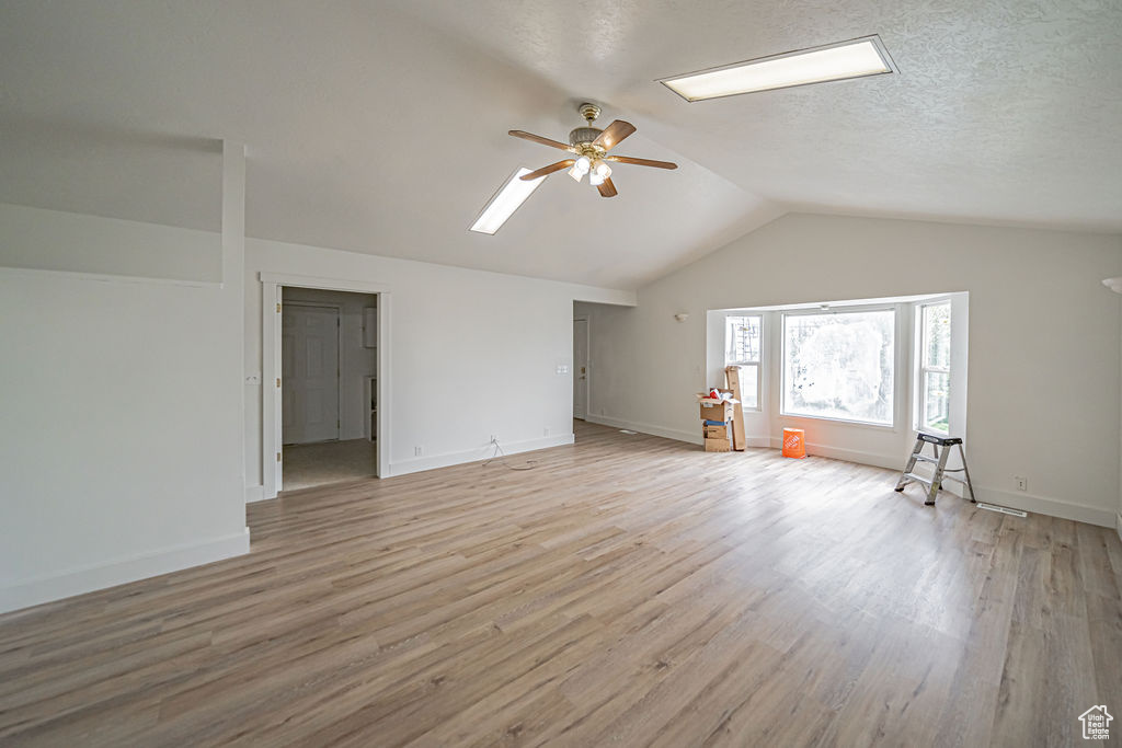 Bonus room with hardwood / wood-style floors, lofted ceiling, ceiling fan, and a textured ceiling