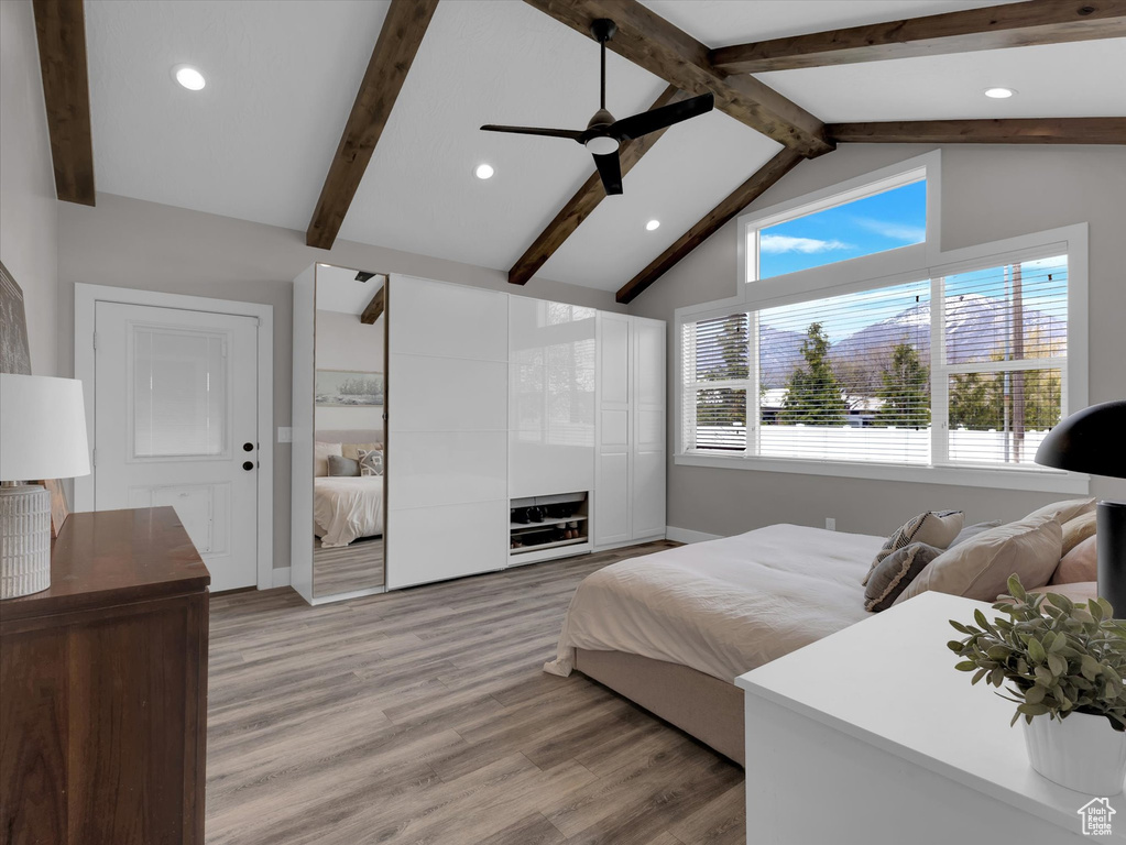 Bedroom featuring light hardwood / wood-style flooring, ceiling fan, and lofted ceiling with beams