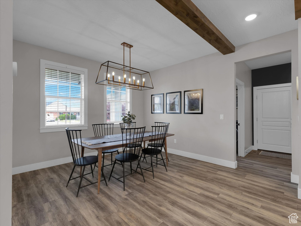 Dining space featuring beam ceiling, an inviting chandelier, and hardwood / wood-style flooring