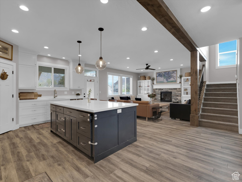 Kitchen with hardwood / wood-style flooring, white cabinets, and a fireplace