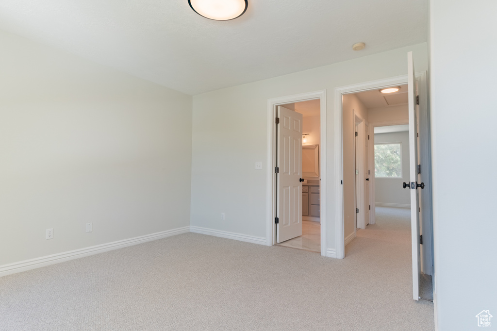 Unfurnished bedroom featuring light colored carpet and connected bathroom