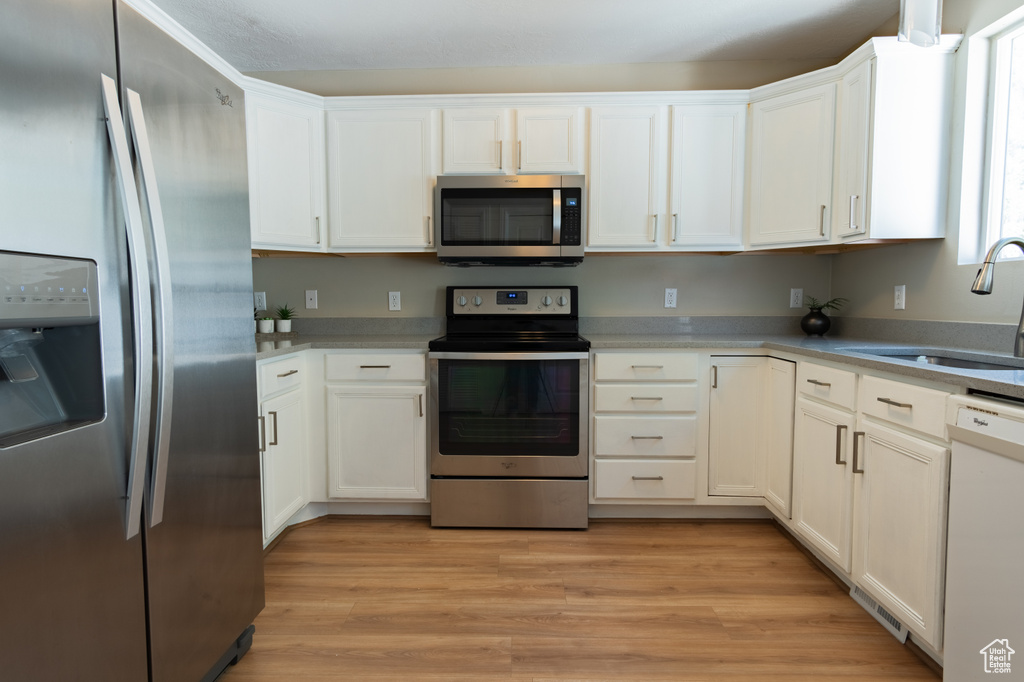 Kitchen featuring sink, light hardwood / wood-style floors, white cabinetry, and stainless steel appliances