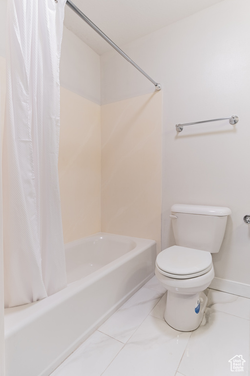 Bathroom featuring shower / tub combo with curtain, toilet, and tile flooring