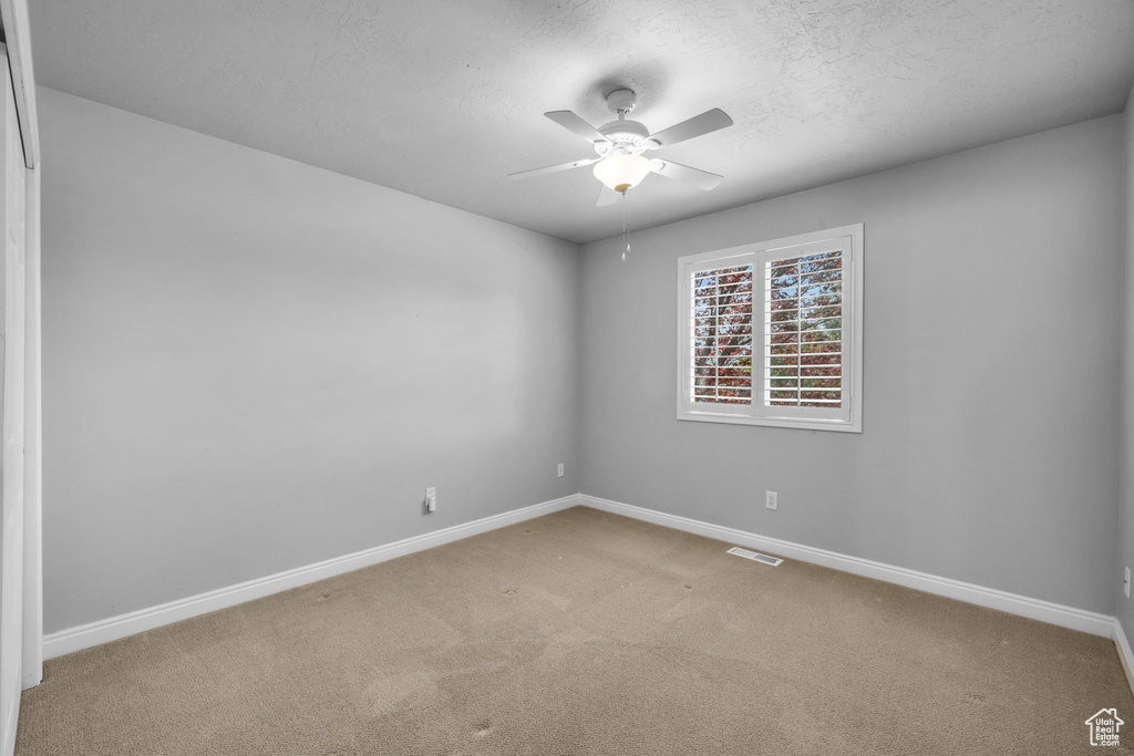 Empty room featuring ceiling fan and carpet