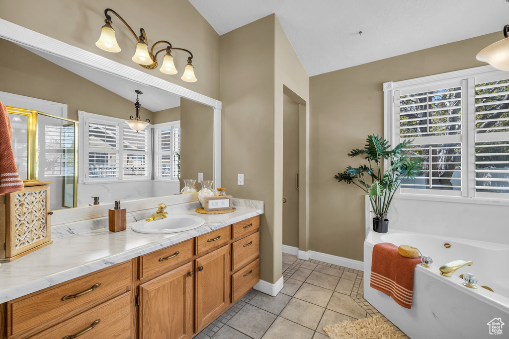 Bathroom with vaulted ceiling, vanity, tile floors, and a wealth of natural light