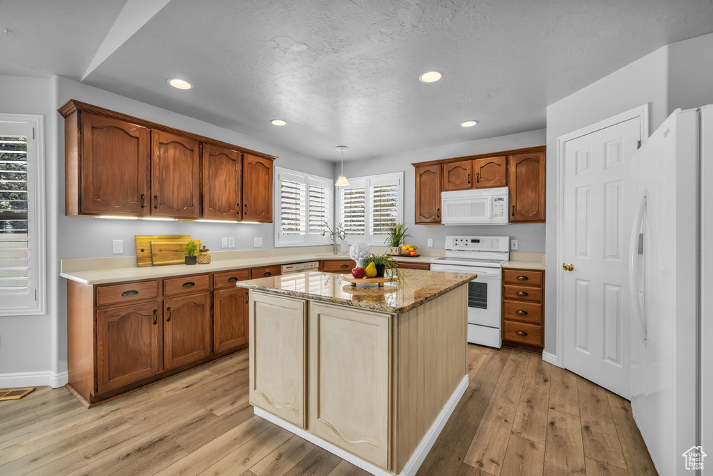 Kitchen with a center island, plenty of natural light, light hardwood / wood-style floors, and white appliances