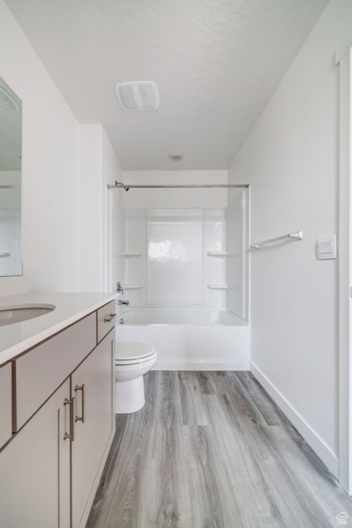 Full bathroom with bathtub / shower combination, vanity, toilet, and hardwood / wood-style flooring