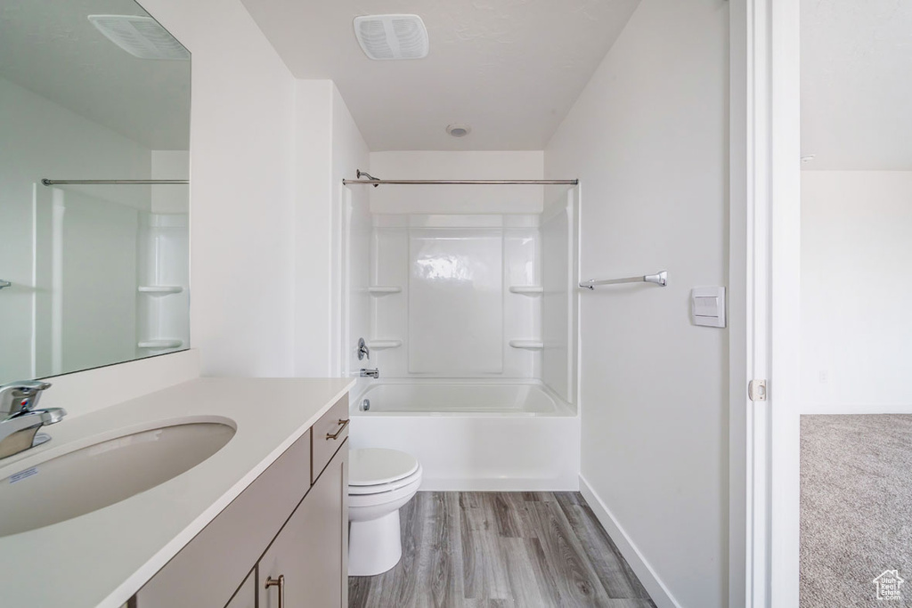 Full bathroom with hardwood / wood-style flooring, washtub / shower combination, vanity, and toilet