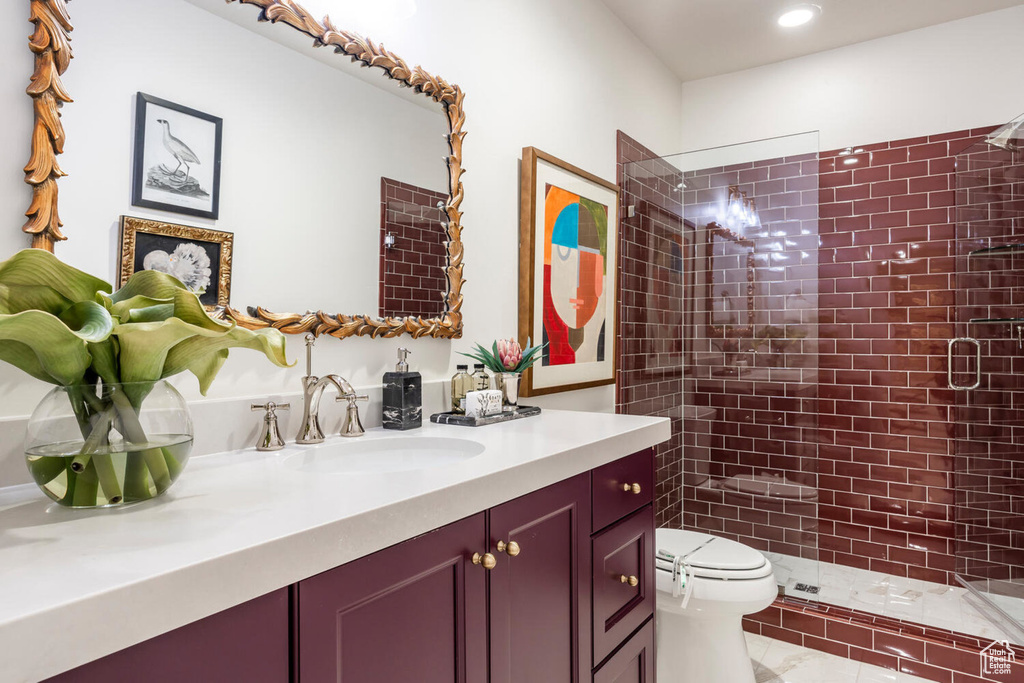 Bathroom featuring tile floors, vanity, toilet, and tiled shower
