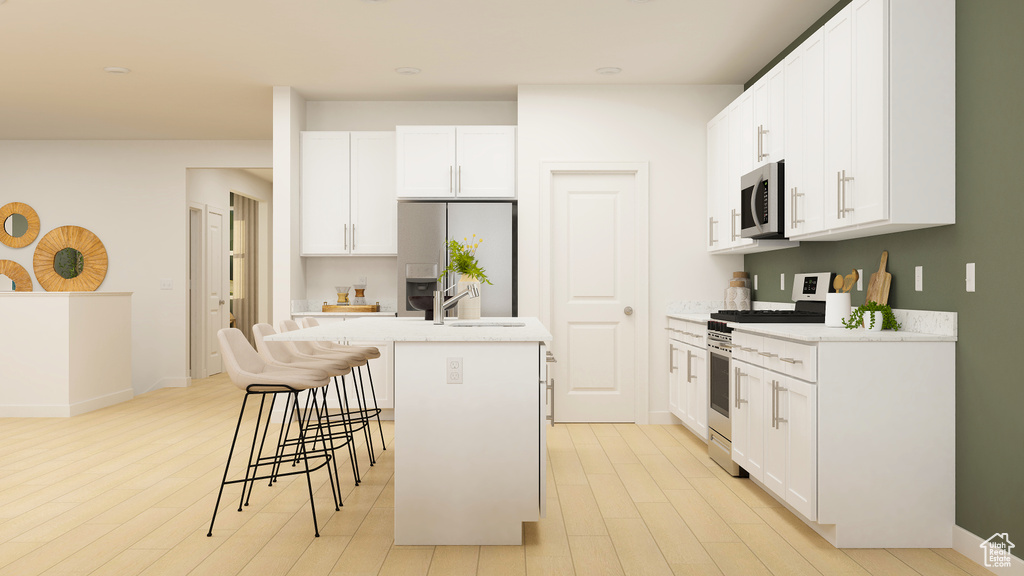 Kitchen featuring appliances with stainless steel finishes, light hardwood / wood-style flooring, white cabinetry, and a kitchen island with sink