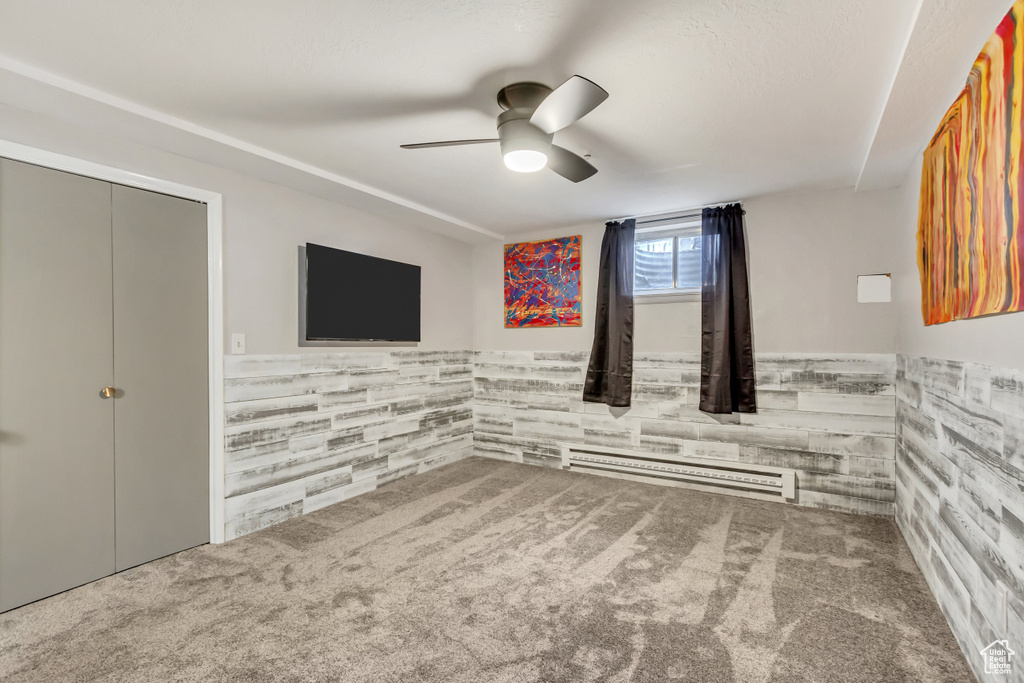Spare room with a baseboard heating unit, ceiling fan, and carpet floors