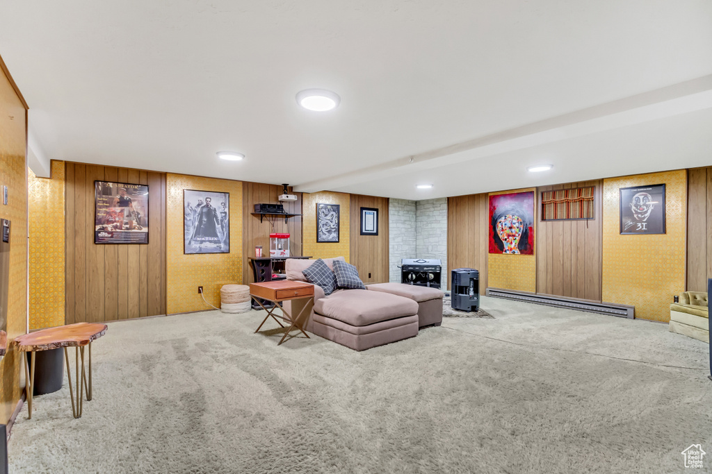 Carpeted living room featuring wooden walls and a baseboard heating unit