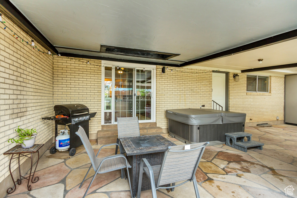 View of patio with grilling area and a hot tub