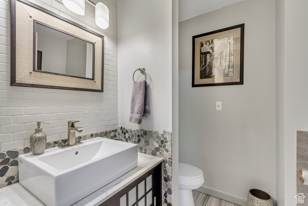 Bathroom featuring tile walls, tasteful backsplash, toilet, and vanity