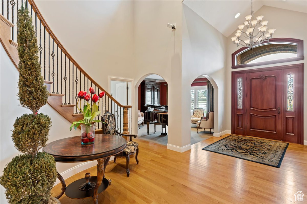 Entrance foyer featuring high vaulted ceiling, a notable chandelier, and light hardwood / wood-style floors