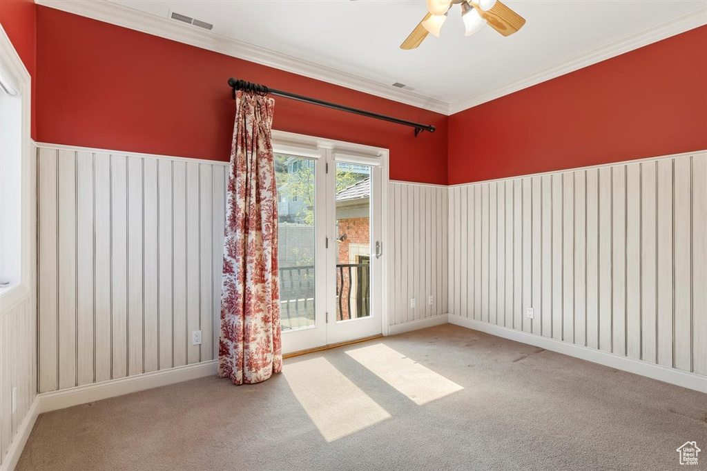 Carpeted spare room featuring ceiling fan and ornamental molding