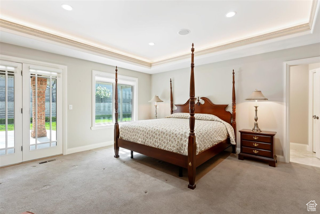 Carpeted bedroom featuring a raised ceiling, crown molding, french doors, and access to exterior