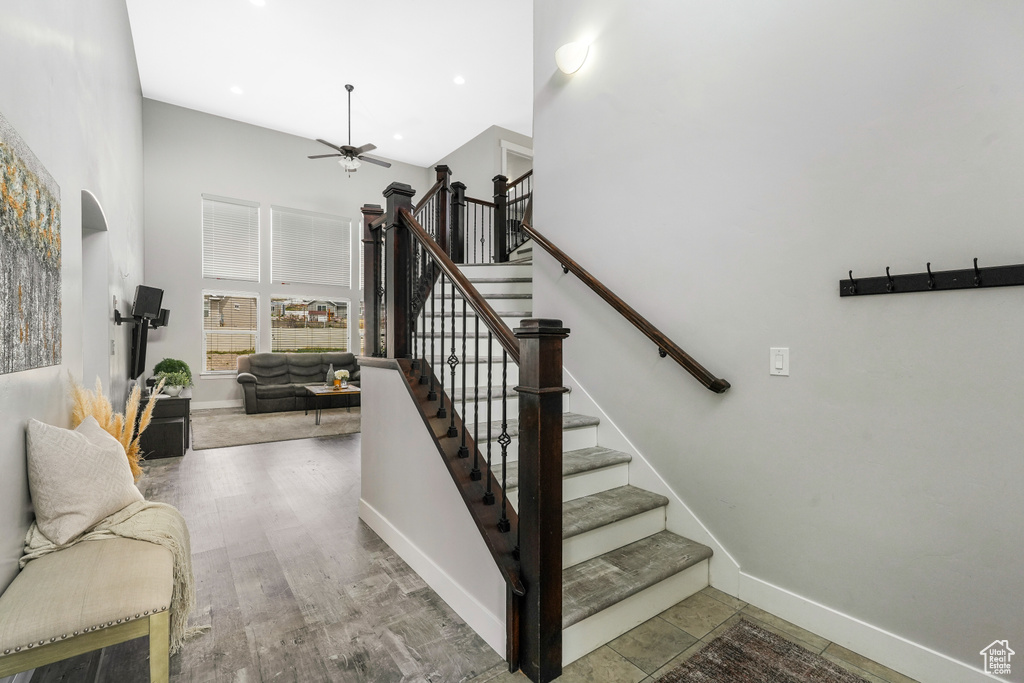 Stairway featuring hardwood / wood-style floors, ceiling fan, and a high ceiling