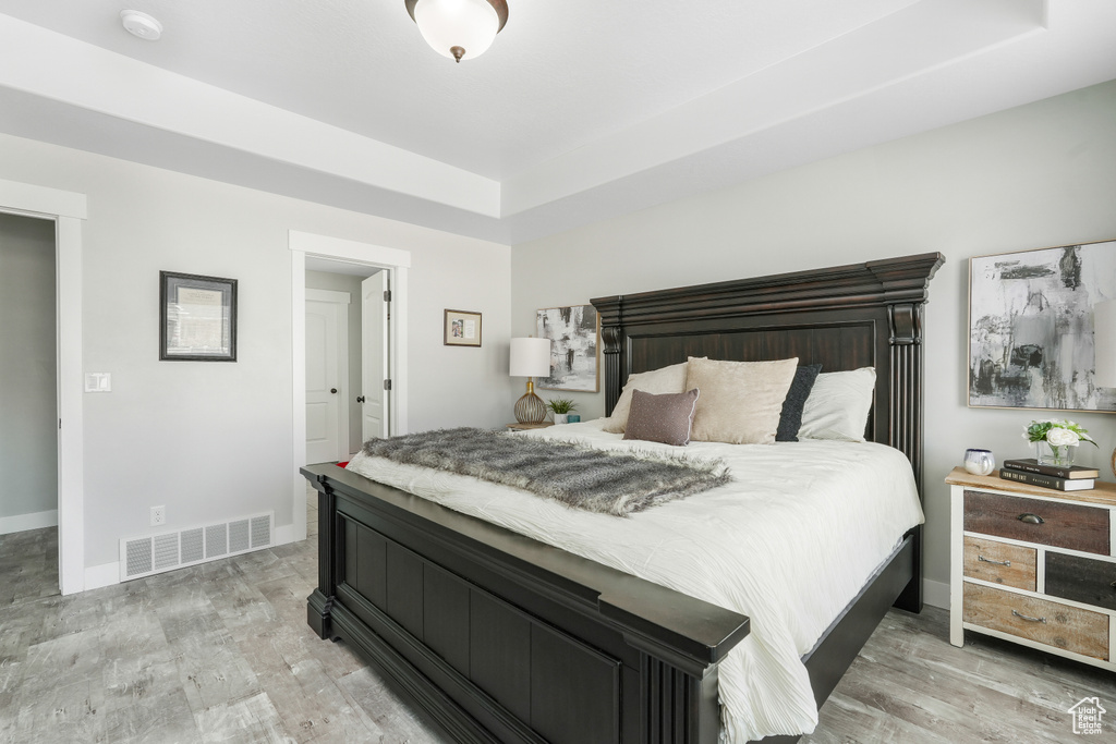 Bedroom featuring light hardwood / wood-style flooring and a raised ceiling