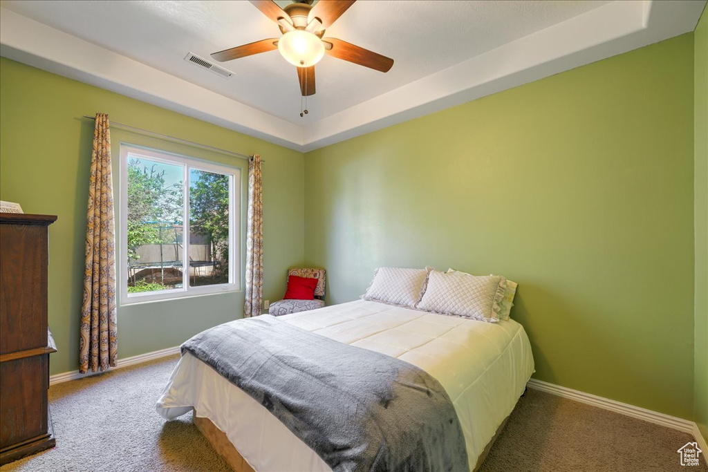 Bedroom with carpet, ceiling fan, and a raised ceiling