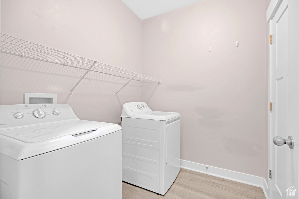 Washroom featuring light wood-type flooring and washing machine and clothes dryer